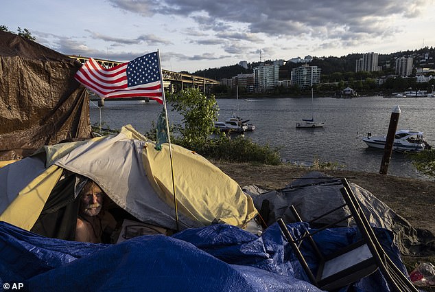 رجل بلا مأوى في خيمته مطلة على النهر في بورتلاند ، أوريغون ، حيث يشتكي السكان من التشرد والجريمة والمخدرات بالإضافة إلى مشاكل اجتماعية أخرى