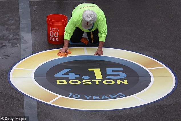 شخص ينظف شعارًا بالقرب من خط النهاية قبل بدء ماراثون بوسطن 127