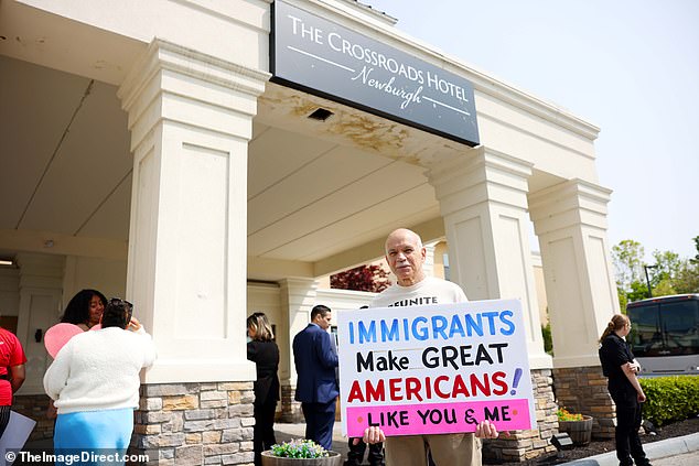 رجل يحمل لافتة للترحيب بالمهاجرين في فندق The Crossroads في نيوبورج ، نيويورك