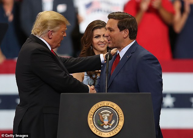 كيسي تقف خلف زوجها وهو يصافح دونالد ترامب ، منافسه الجمهوري الآن ، خلال تجمع حاشد في عام 2018.