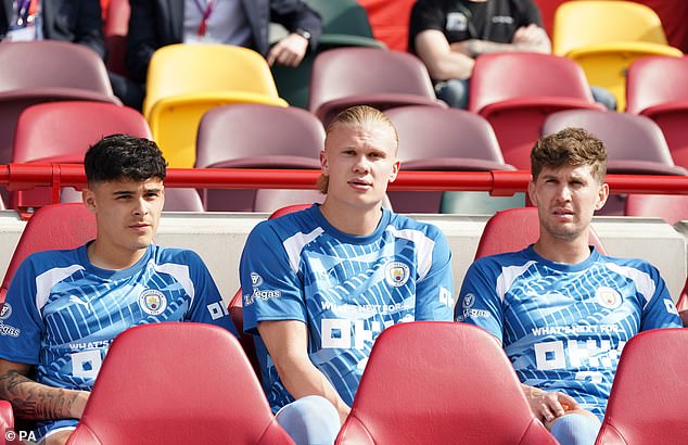 روبرتسون (يسار) يجلس على مقاعد البدلاء مع النجم النرويجي إيرلينج هالاند (وسط) وجون ستونز خلال مباراة في الدوري الإنجليزي الممتاز على ملعب جيتيك كوميونيتي ، لندن.