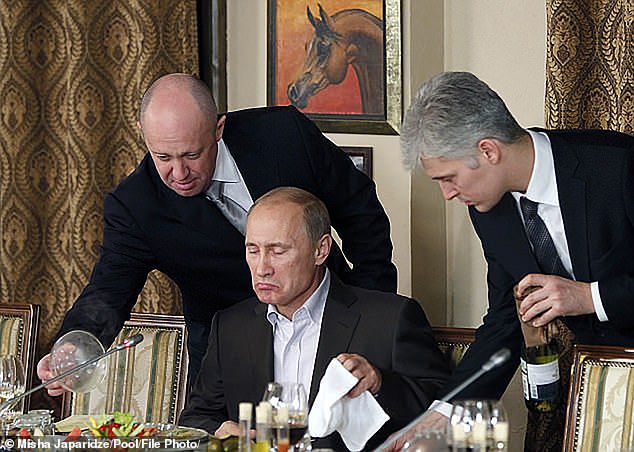 يفغيني بريغوزين (يسار) يساعد فلاديمير بوتين خلال (في الوسط) عشاء مع علماء وصحفيين أجانب في مطعم Cheval Blanc في مبنى مجمع الفروسية خارج موسكو في نوفمبر 2011