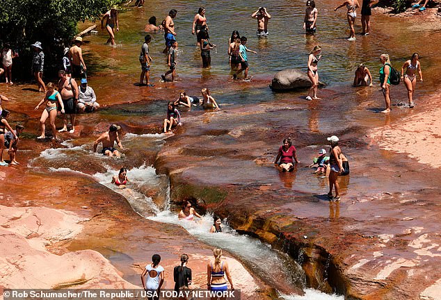 في الصورة: العشرات من الناس يستريحون في مياه أوك كريك يوفرون ملاذًا من الحرارة الشديدة في سيدونا ، أريزونا في Slide Rock State Park