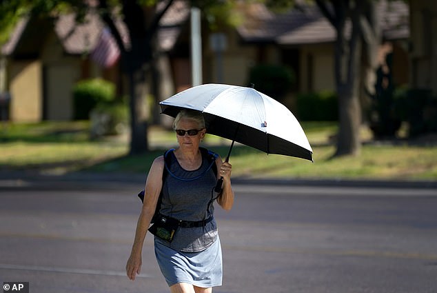 امرأة تستخدم مظلة للظل لمكافحة ارتفاع درجات الحرارة في فينيكس يوم الاثنين