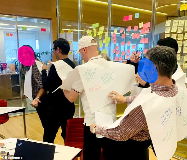 صورة تظهر مجموعة من الموظفين يرتدون المرايل الورقية الورقية أثناء كتابة الرسائل عليهم حول ما `` يقدرونه أكثر '' عن زملائهم