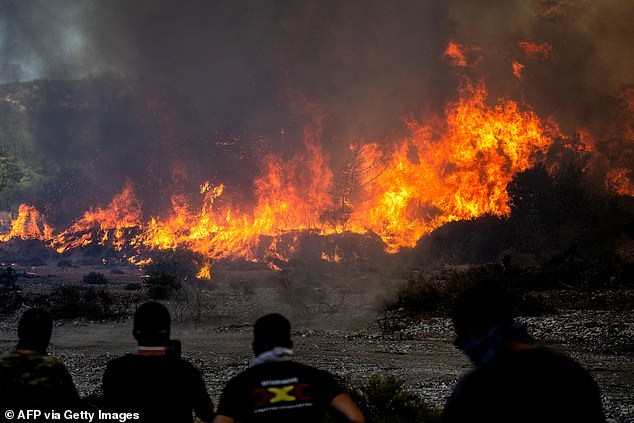 السكان المحليون يشاهدون حرائق الغابات بالقرب من قرية فاتي ، شمال مدينة غينادي الساحلية ، في الجزء الجنوبي من جزيرة رودس اليونانية في 2 يوليو.