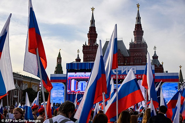 أشخاص يلوحون بالأعلام الروسية يحضرون حفلًا موسيقيًا مخصصًا للذكرى الأولى لضم أربع مناطق من أوكرانيا التي تسيطر عليها القوات الروسية