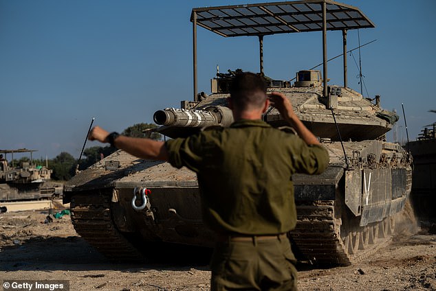 جندي إسرائيلي يوجه سائق دبابة بالقرب من حدود شمال غزة، 17 نوفمبر، 2023.