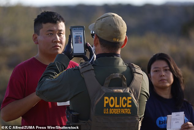 مهاجر من الصين يطلب اللجوء يحمل جواز سفره وأوراقه أثناء تصويره من قبل دورية الحدود الأمريكية في ديسمبر 2023