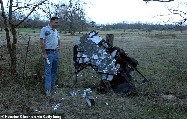 ماك باول يقف بجانب ما يعتقد أنه الجناح الأيسر المتضرر من مكوك الفضاء كولومبيا، على ممتلكاته في مقاطعة ناكوجدوشس، تكساس في عام 2003.