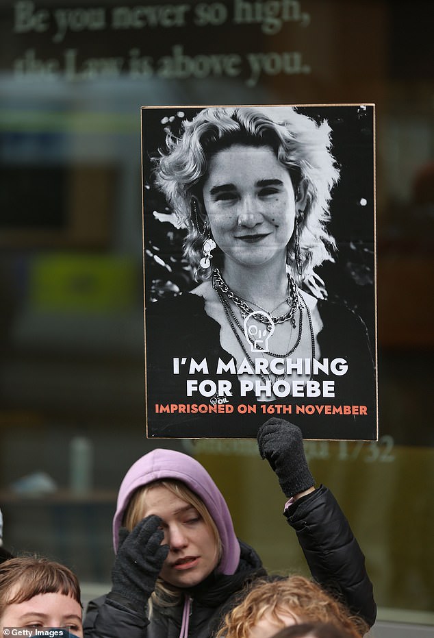 أحد مؤيدي منظمة Just Stop Oil يحمل صورة الناشطة فيبي بلامر في ديسمبر/كانون الأول بعد أن تم سجنها بسبب الاحتجاجات المتكررة