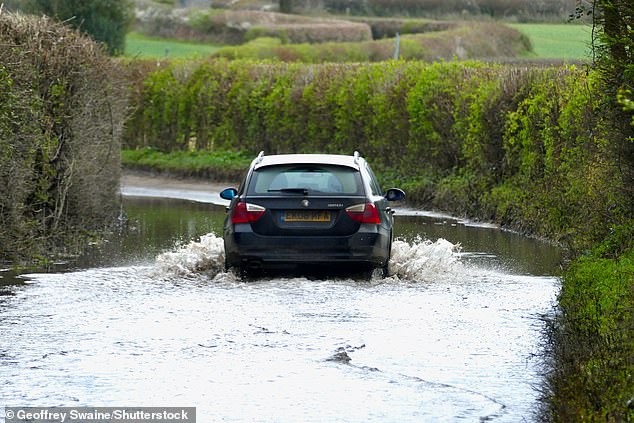 في الصورة: سيارة تسير عبر ممر ريفي مشبع بالمياه في أوكسفوردشاير يوم الجمعة