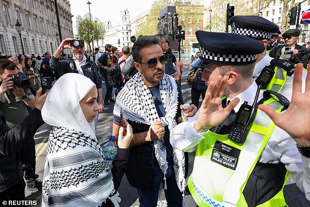 أنصار مؤيدون للفلسطينيين يتحدثون مع ضابط شرطة خلال مظاهرة نظمتها منظمة Turning Point UK في لندن يوم السبت