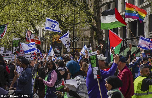 أشخاص يحملون مجموعة متنوعة من الأعلام واللافتات في الاحتجاجات في لندن يوم السبت، بما في ذلك الأعلام الوطنية لفلسطين وإسرائيل