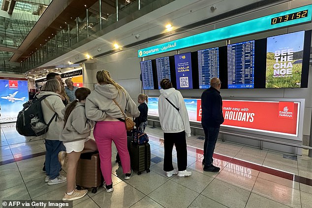 مسافرون يتحققون من معلومات الرحلة على الشاشات في مطار دبي الدولي يوم الأربعاء