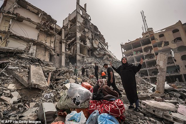 فلسطينيون يتفقدون الأضرار التي لحقت بمبنى في مدينة النصيرات وسط قطاع غزة في 18 أبريل