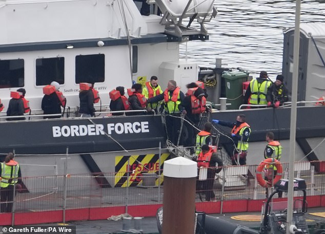 وشوهد مسؤولون بريطانيون وهم يرشدون المهاجرين الذين يرتدون سترات النجاة من القارب