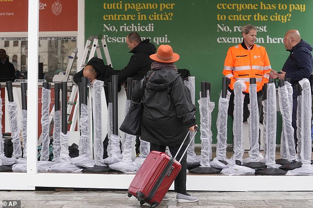 أعلاه، عمال يقومون بإعداد مكاتب أمين صندوق الضرائب السياحية خارج محطة القطار الرئيسية في البندقية