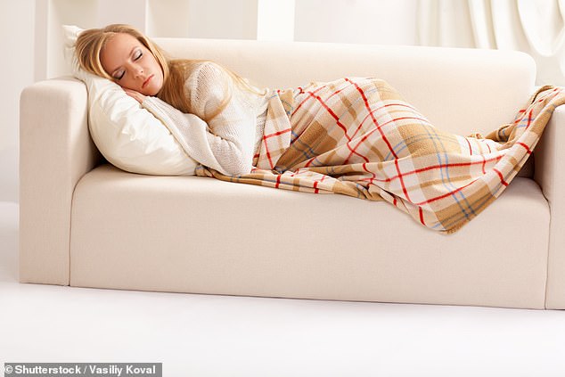 امرأة تنام على أريكة تحت بطانية.  يقول العلماء إن البطانيات الموزونة تؤدي إلى إطلاق مواد كيميائية تشعرك بالسعادة في الدماغ، والتي تتفاعل مع ضغط البطانية كما هو الحال مع العناق أو الاحتضان (صورة مخزنة)