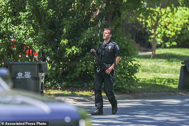 ضابط شرطة في شارلوت مكلنبورغ يحمل مسدسًا أثناء سيره في الحي الذي وقع فيه إطلاق نار متورط من قبل ضابط في شارلوت