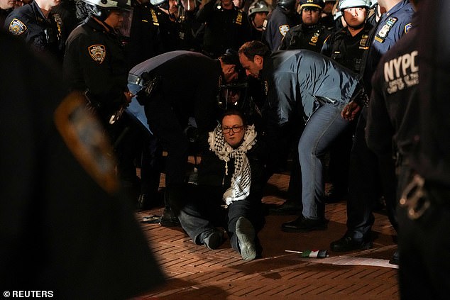 شوهد ضباط شرطة نيويورك وهم يعتقلون متظاهرة وهي تجلس على الأرض وكوفية حول رقبتها
