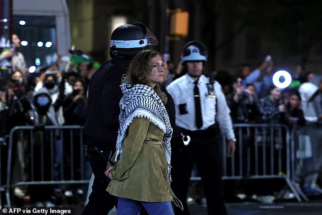وشوهدت متظاهرة أخرى ويداها خلف ظهرها وكوفية حول رقبتها بينما كان ضابط يمشي معها