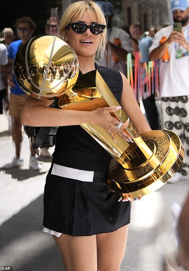كاميلا كابيلو تحمل كأس بطولة Larry O 'Brien NBA بفستان أبيض وأسود