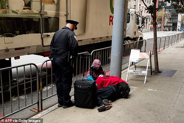 ضابط قسم شرطة سان فرانسيسكو يطلب من شخصين يجلسان على الرصيف التحرك