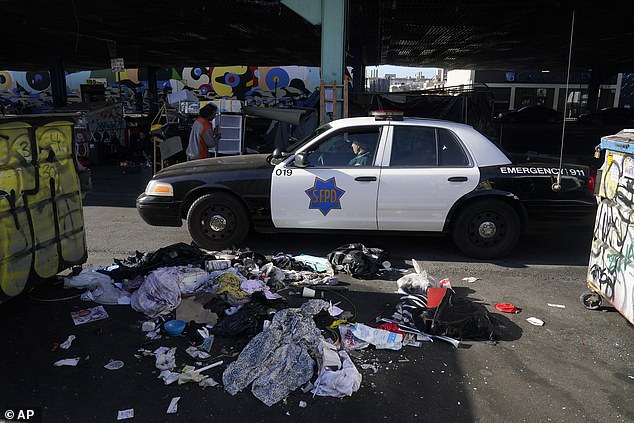 سيارة تابعة لقسم شرطة سان فرانسيسكو تمر عبر مخيم للمشردين يتم تنظيفه في سان فرانسيسكو