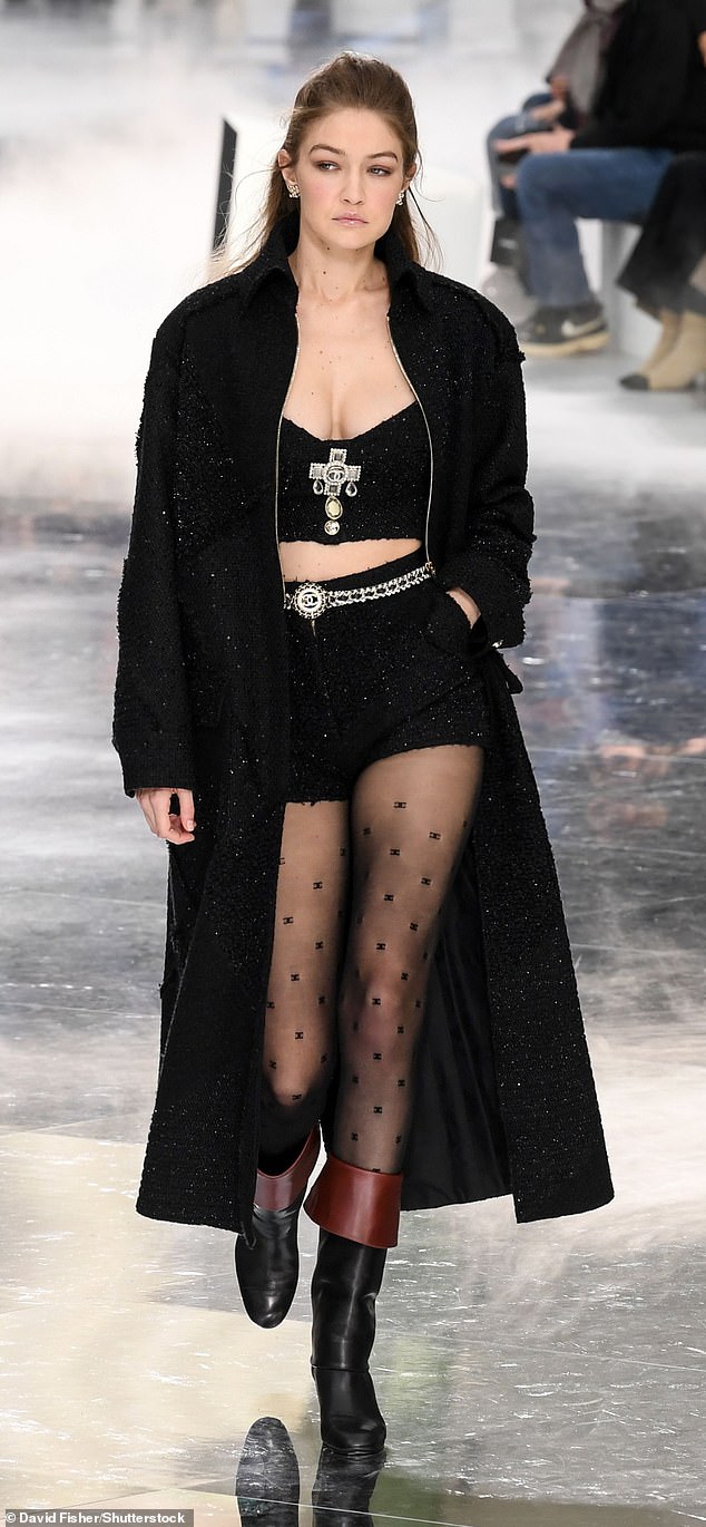 مشيت جيجي حديد لصالح شانيل في أسبوع الموضة في باريس عام 2020 مرتدية جوارب سوداء شفافة مطرزة بشعار دار الأزياء الفرنسية