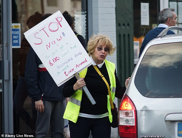 امرأة تحذر سائقي السيارات من الغرامات المحتملة بسبب LTN في تشيسويك، غرب لندن، في عام 2020